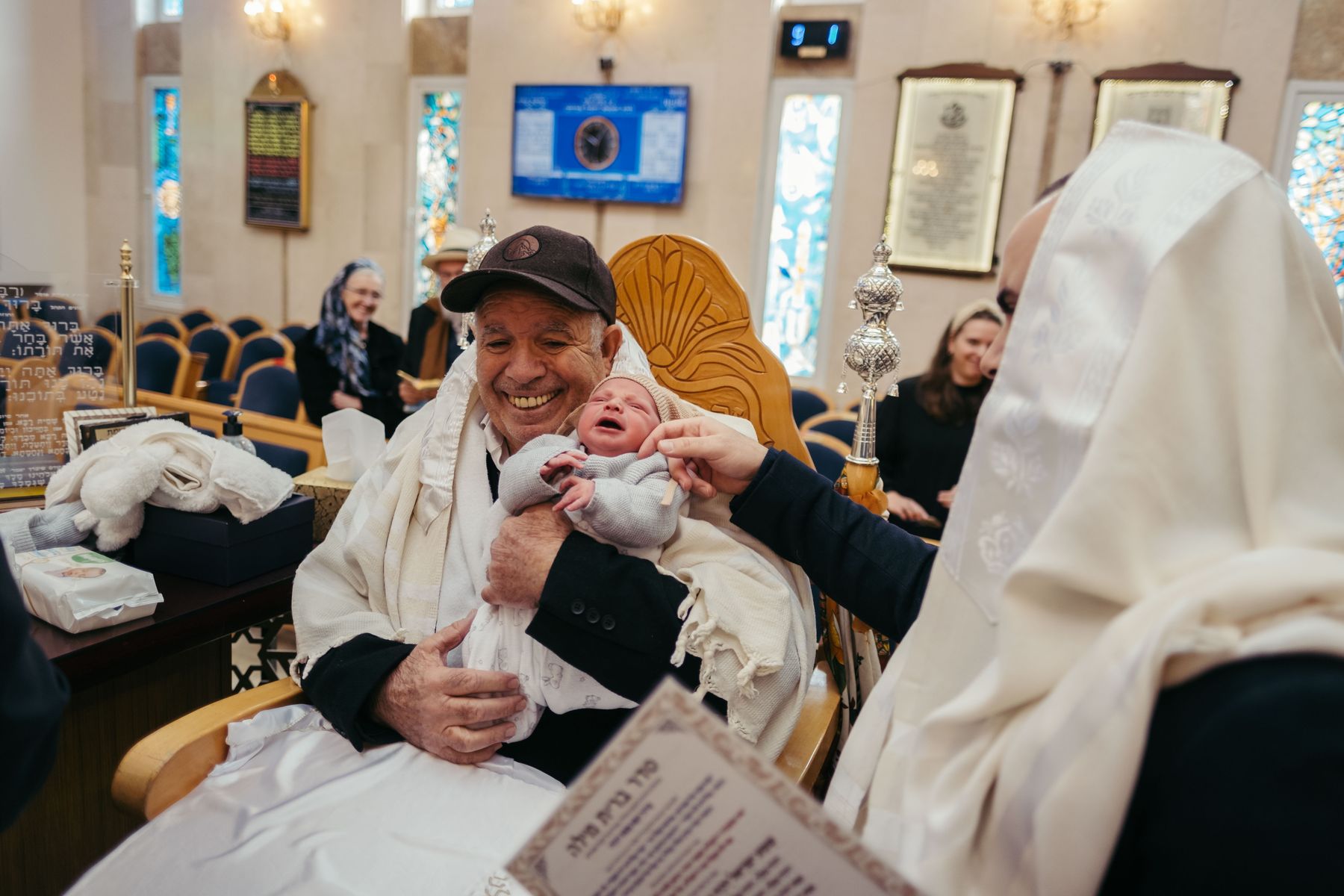 Grandfather as sandek holding the baby at a brit milah in shul