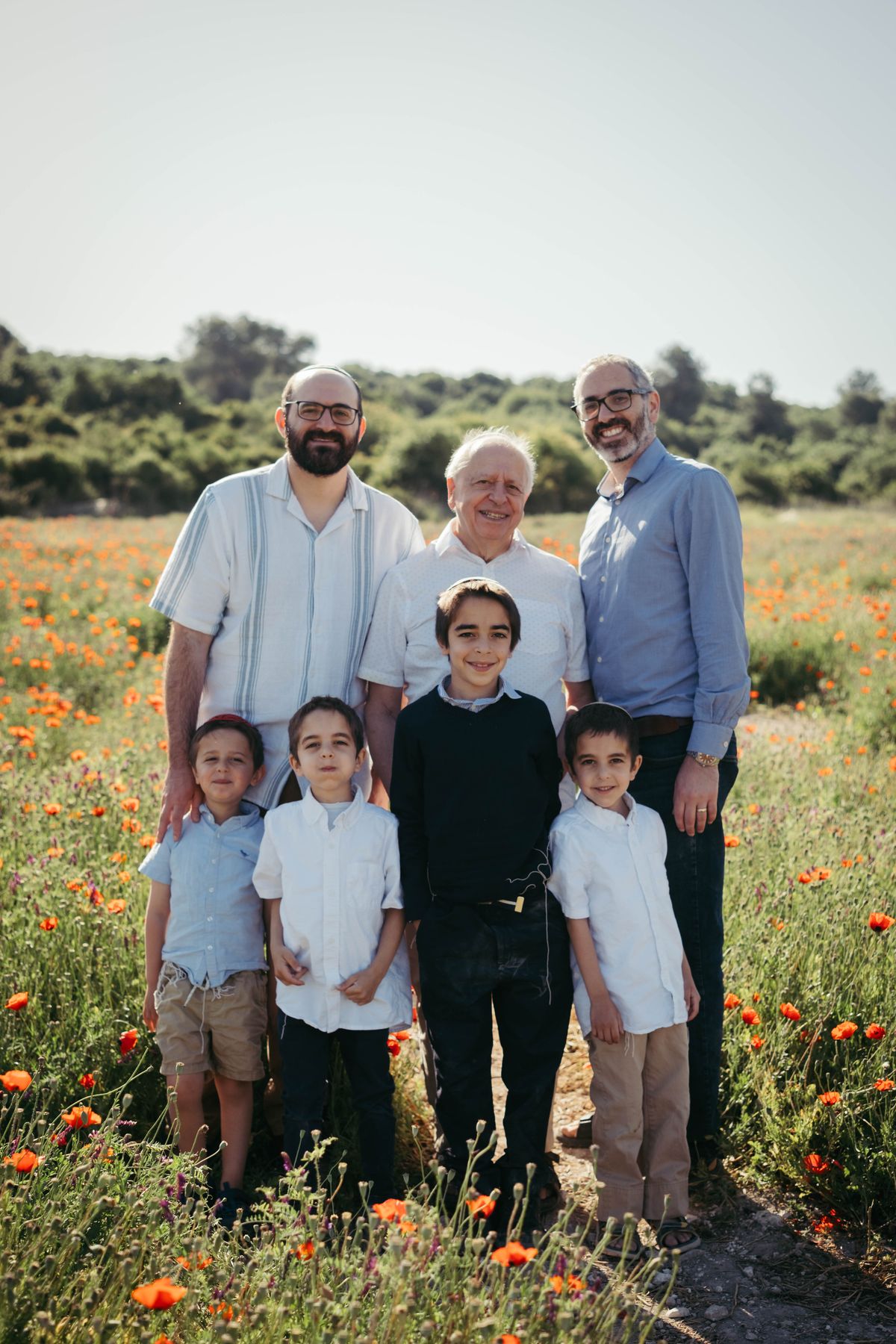 Three generations of a family standing in a field of red poppies
