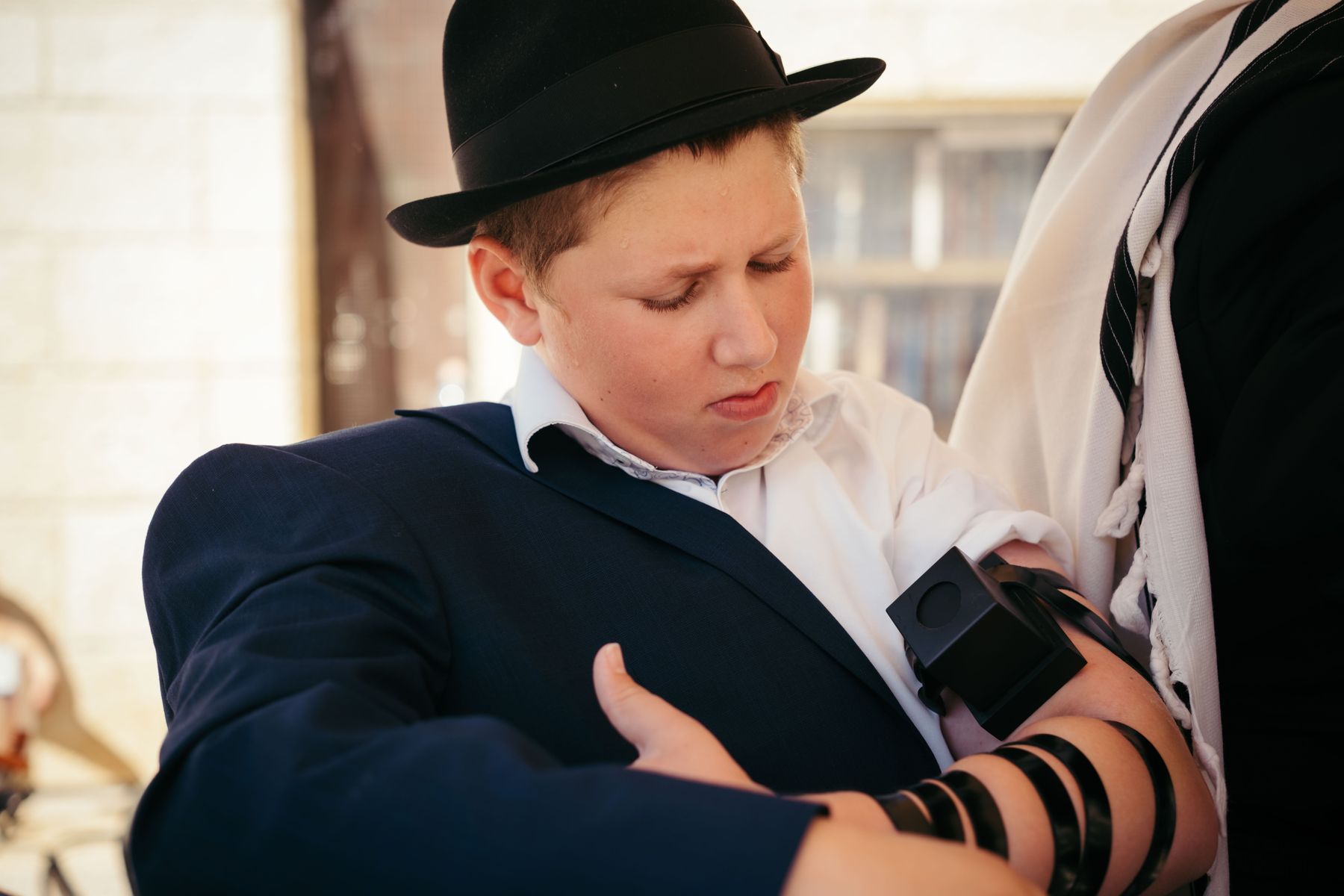 Bar mitzvah boy putting on tefillin at the Western Wall
